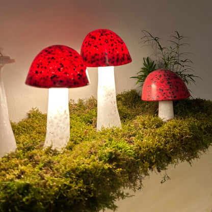 Decorative red mushroom lights on a grassy surface with a neutral background
