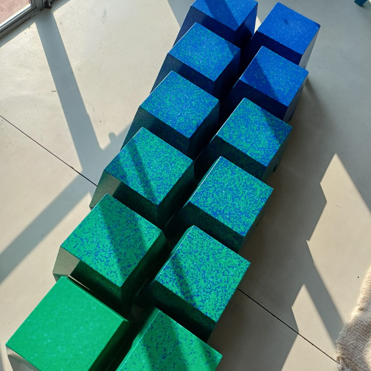 A set of twelve cube-shaped stools arranged in two rows,. 
